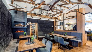 A modern restaurant interior with exposed wooden beams, dark stone walls, and a variety of seating options including tables and booths. - Stemplinger Hansl (Hauzenberg)