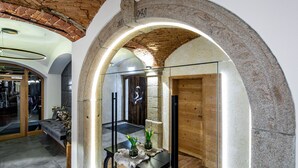 An interior with a stone archway, a wooden door, and a glass partition. - Stemplinger Hansl (Hauzenberg)