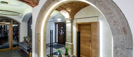 Un interior con un arco de piedra, una puerta de madera y un separador de vidrio.