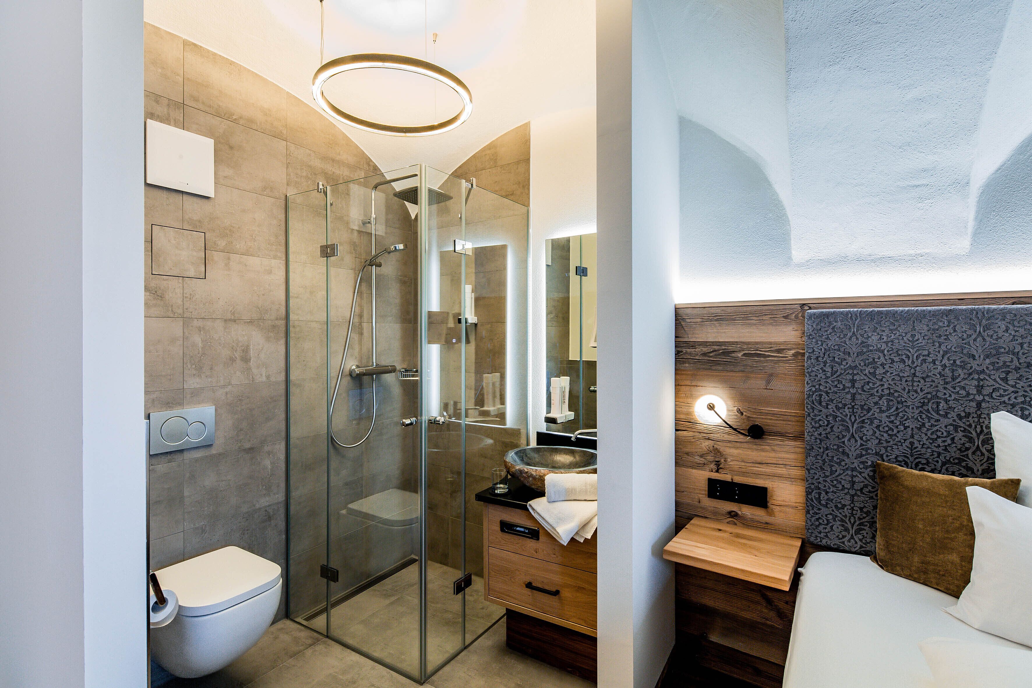 A modern bathroom with a glass-enclosed shower, a toilet, and a vanity with a wooden countertop.