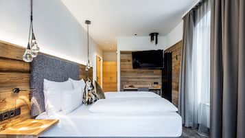 Una habitación de hotel moderna con una cama grande, un cabecero de madera, un televisor y un escritorio con una silla.