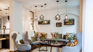 A modern living room with a sofa set, two armchairs, and a coffee table. There are pendant lights hanging from the ceiling and a small side table with a plant. - Stemplinger Hansl (Hauzenberg)
