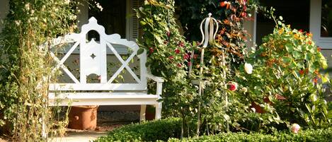 A white bench in a garden with roses and a trellis.