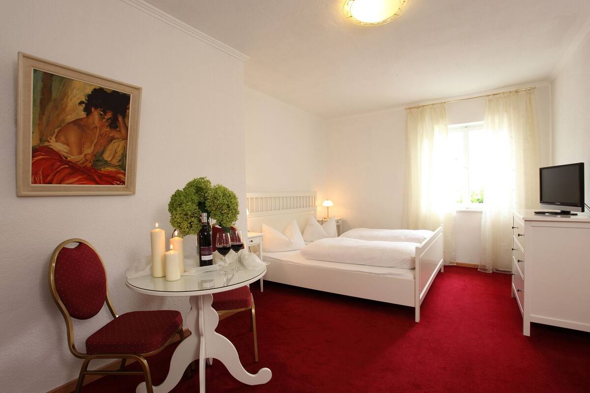 Une chambre d’hôtel avec un lit, un bureau et une chaise, une télévision et un tableau au mur.