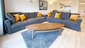 A modern living room with a sectional sofa, a wooden coffee table, and a blue rug. - NEW FOR 2020 - 3 Harvest Moon is a stunning fully refurbished 2 bedroom, 2 en suite bathroom apartme (Newquay)