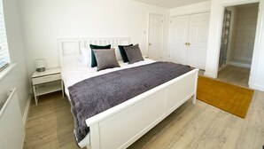 A bedroom with a bed, nightstand, and a door leading to a bathroom. - NEW FOR 2020 - 3 Harvest Moon is a stunning fully refurbished 2 bedroom, 2 en suite bathroom apartme (Newquay)