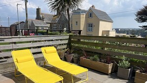A patio with two yellow lounge chairs, a wooden fence, and potted plants. - NEW FOR 2020 - 3 Harvest Moon is a stunning fully refurbished 2 bedroom, 2 en suite bathroom apartme (Newquay)