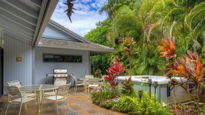 An outdoor patio with a grill, seating, and lush tropical plants. - Spacious Poipu Beach Home near Hyatt-Remodeled Kitchen & Bathrooms Large Hot Tub (Koloa)