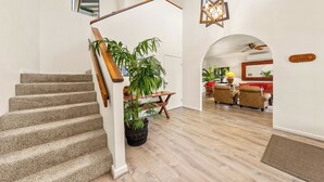 A staircase with carpeted steps, a wooden handrail, and a potted plant. - Spacious Poipu Beach Home near Hyatt-Remodeled Kitchen & Bathrooms Large Hot Tub (Koloa)