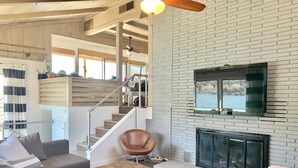A modern living room with a fireplace, a staircase, and a view of the outdoors.