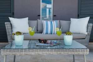 Une table en verre avec deux boissons, un magazine et des lunettes de soleil.