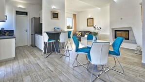 Una cocina moderna con armarios blancos y un comedor con sillas azules.