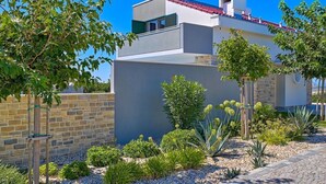 Un edificio moderno con techo plano, pared de piedra y camino de grava.