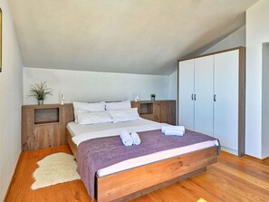 Une chambre à coucher avec un lit en bois, du linge de lit blanc, un tapis moelleux et une armoire.