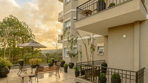 A balcony with a wooden bench, potted plants, and a table with chairs. - Pousada La Bas Suites de Montagne (Campos do Jordão)