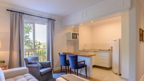 A modern living room with a sofa, a coffee table, and a dining area with blue chairs. - Pousada La Bas Suites de Montagne (Campos do Jordão)
