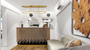 A modern interior with a wooden reception desk, a sofa, and a large wooden wall art piece. - Villa Monument Hotel (Lagos)