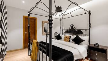 Una cama con dosel, una mesita de noche y una puerta de madera.