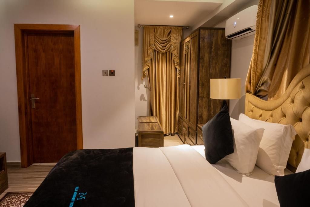A hotel room with a bed, a wooden door, a wardrobe, and a curtain.