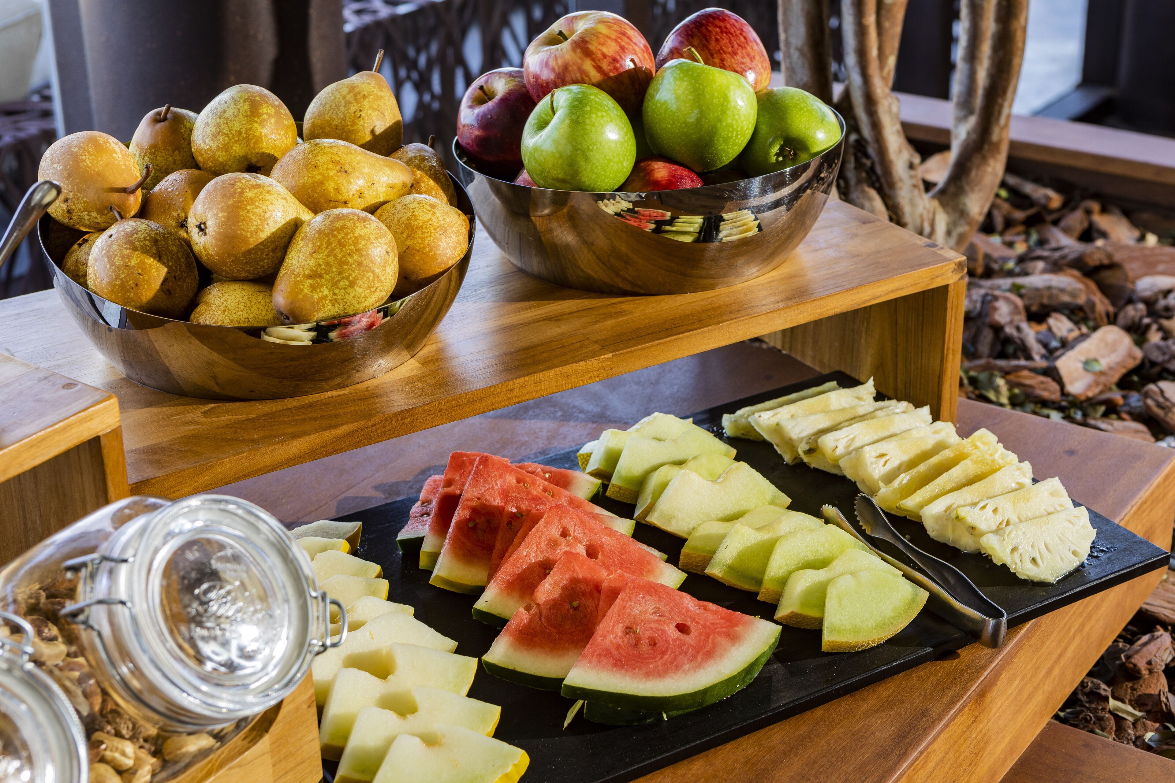 Exposição de frutas com peras, maçãs e fatias de melancia sobre uma mesa de madeira.