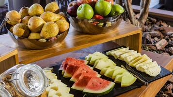 Exposição de frutas com peras, maçãs e fatias de melancia sobre uma mesa de madeira.