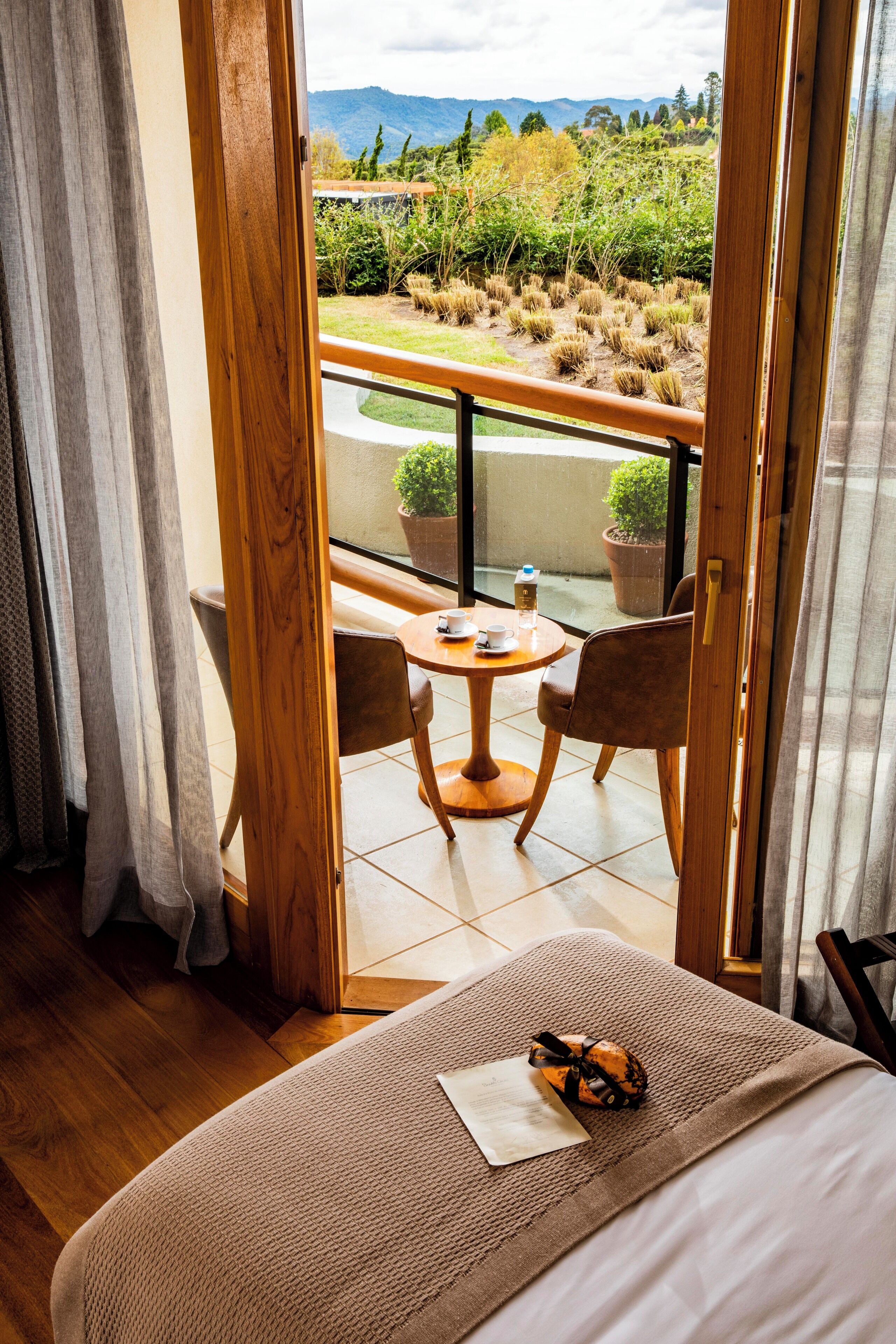 Une chambre avec un lit, une petite table avec des chaises et un balcon donnant sur l’extérieur.