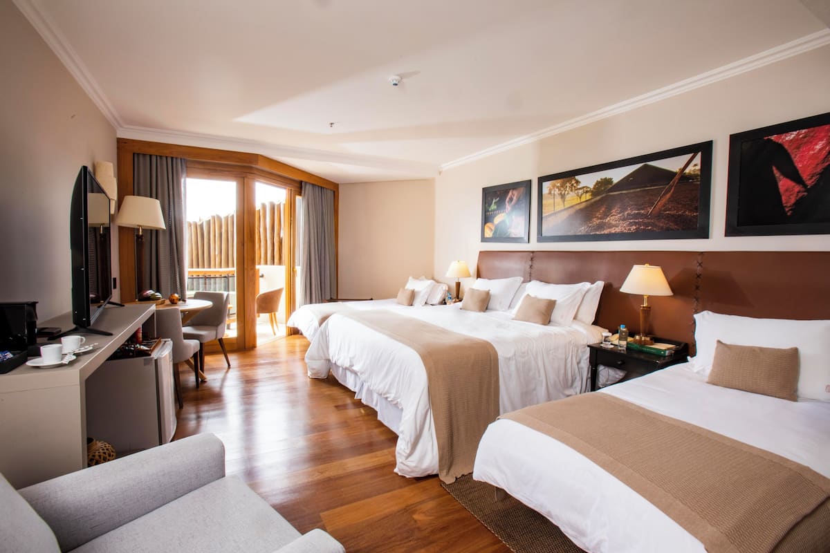 A hotel room with two beds, a desk, a chair, and a TV.