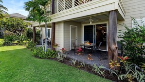 A two-story house with a balcony, a patio with outdoor furniture, and a well-maintained garden. - Waikoloa Beach Villas M2 (Waikoloa)