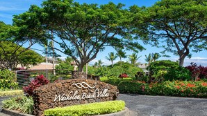 A sign for Waikoloa Beach Villas with a landscaped area featuring various plants and trees. - Waikoloa Beach Villas M2 (Waikoloa)