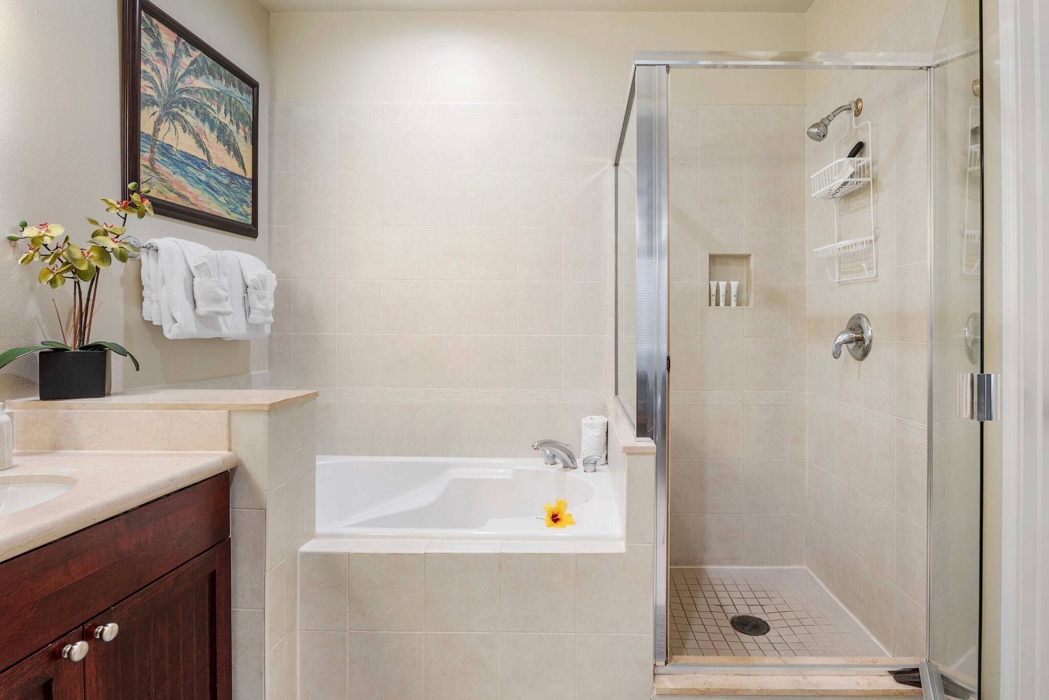 Une salle de bain avec une baignoire, une douche et un lavabo. Il y a un tableau encadré au mur, une plante et un porte-serviettes.