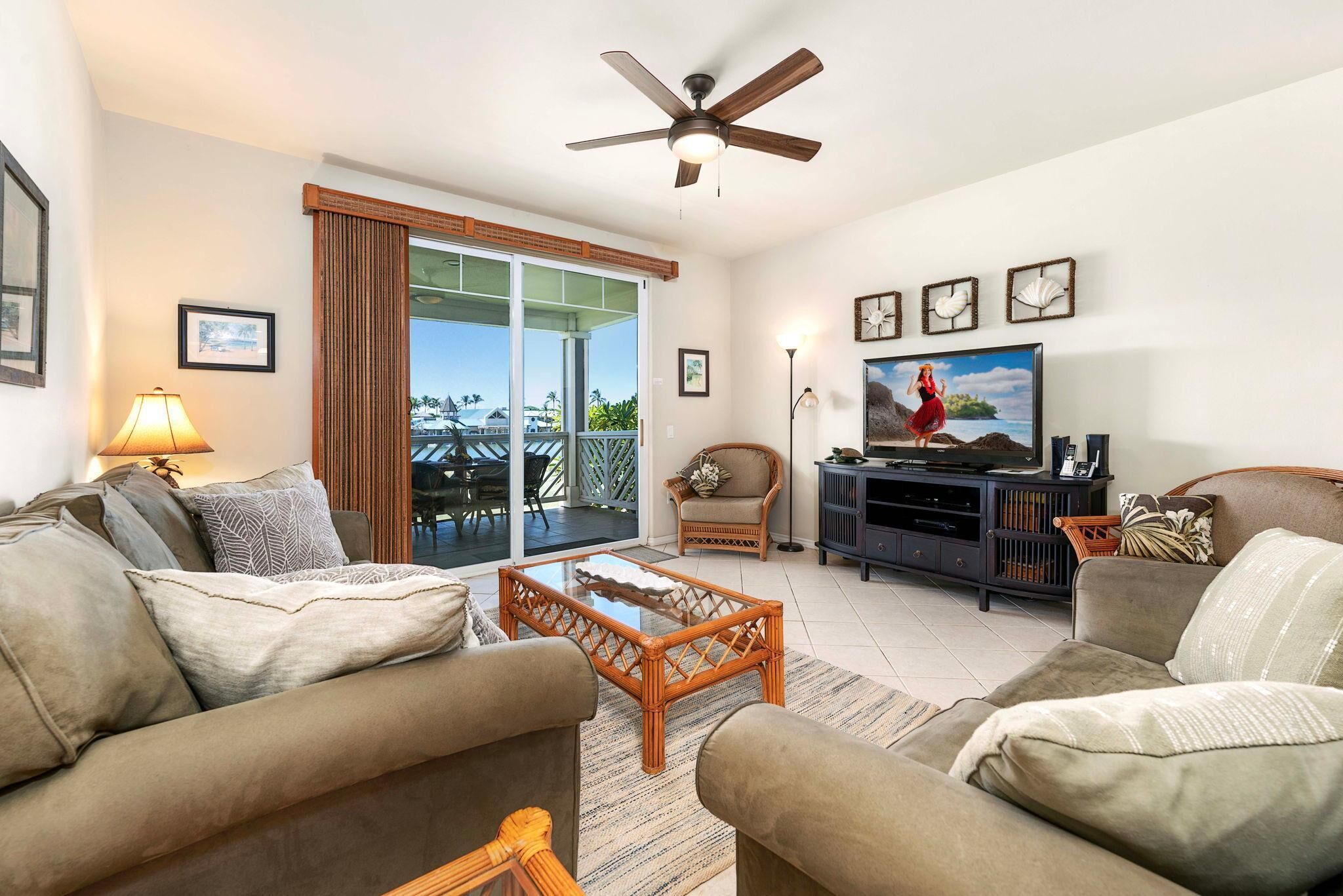 A living room with a sofa, a coffee table, a television, and a ceiling fan.