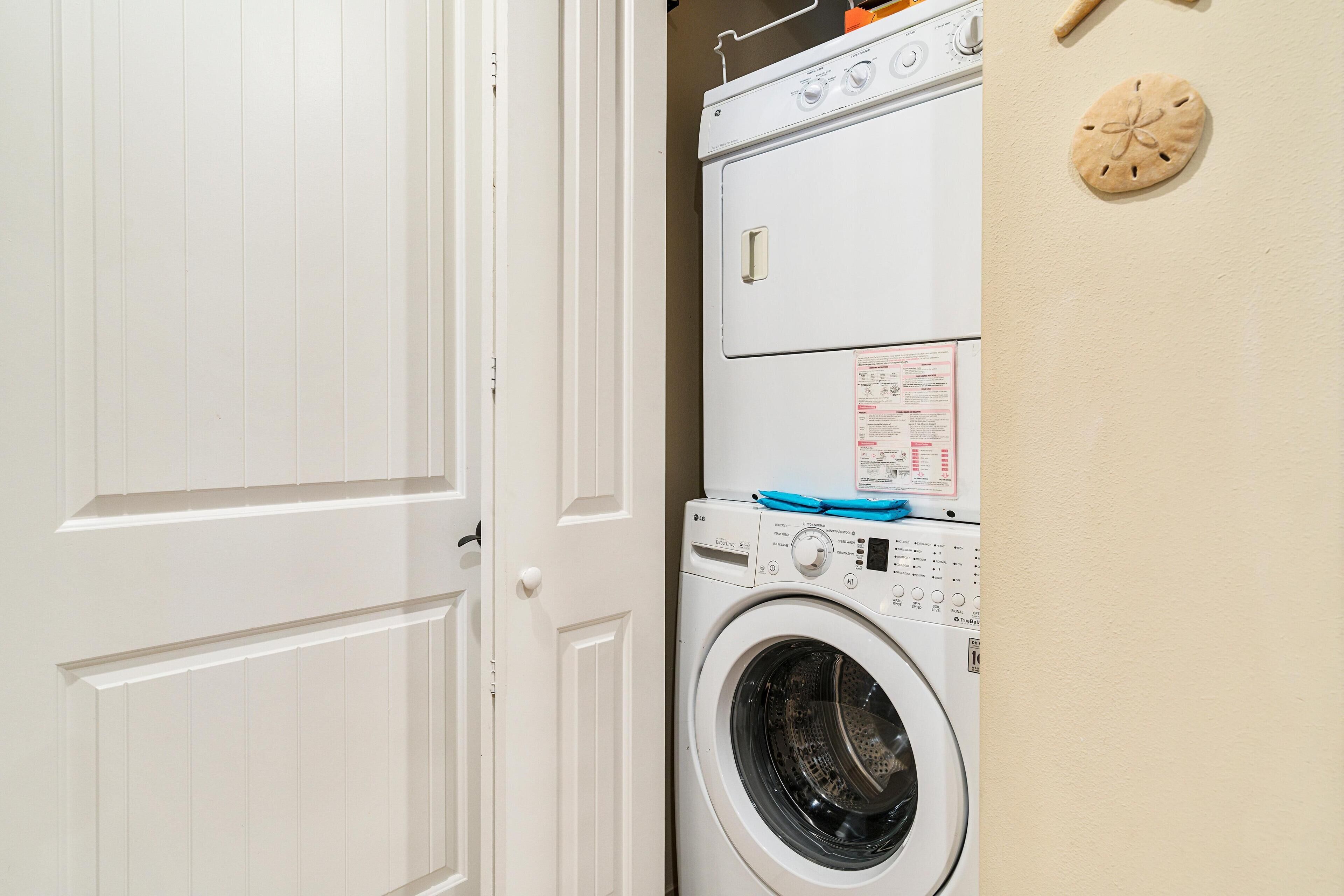 A laundry area with stacked washers and dryers, a door, and a wall-mounted clock.