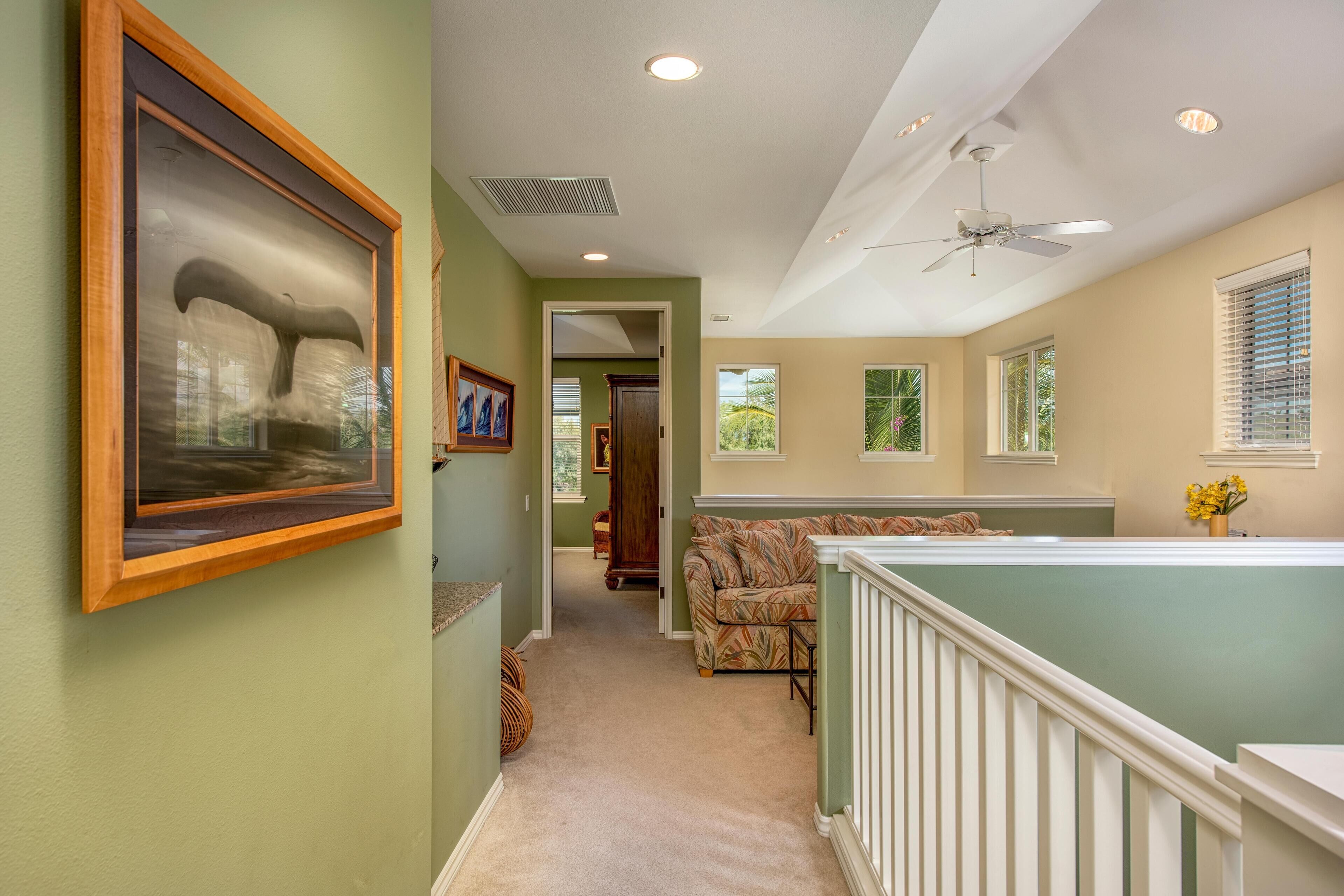 A hallway with a framed artwork, a ceiling fan, and a couch.