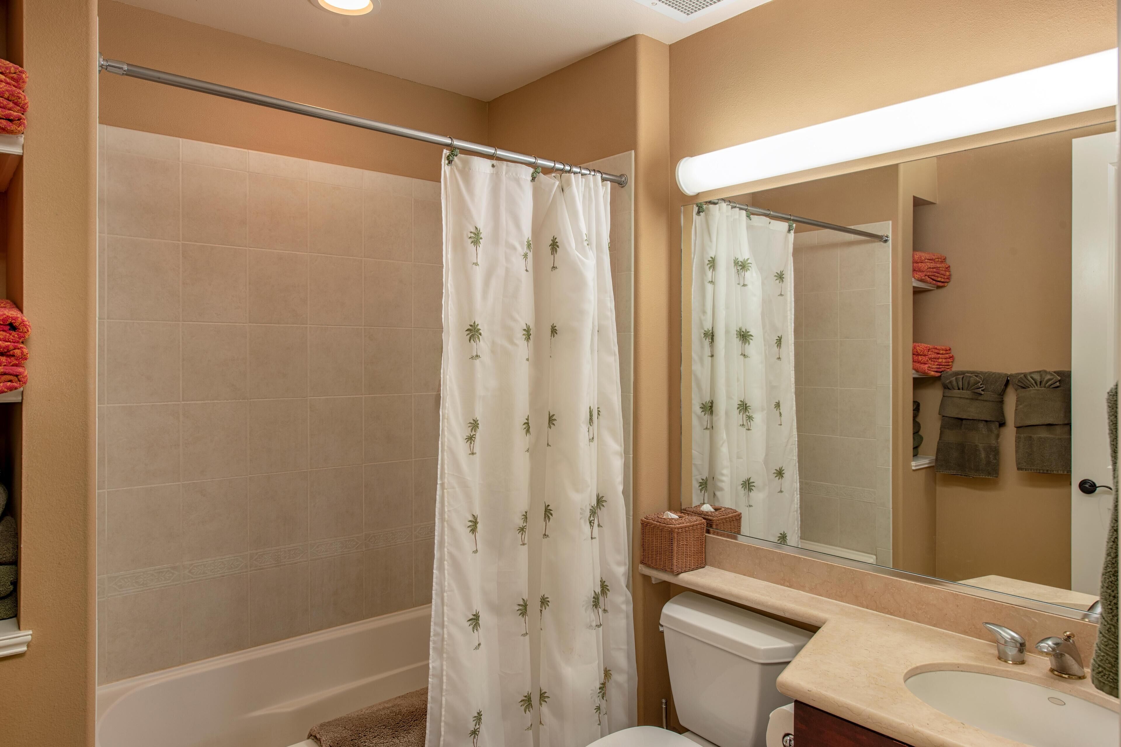 Un baño con cortina de ducha, inodoro, lavabo y espejo.