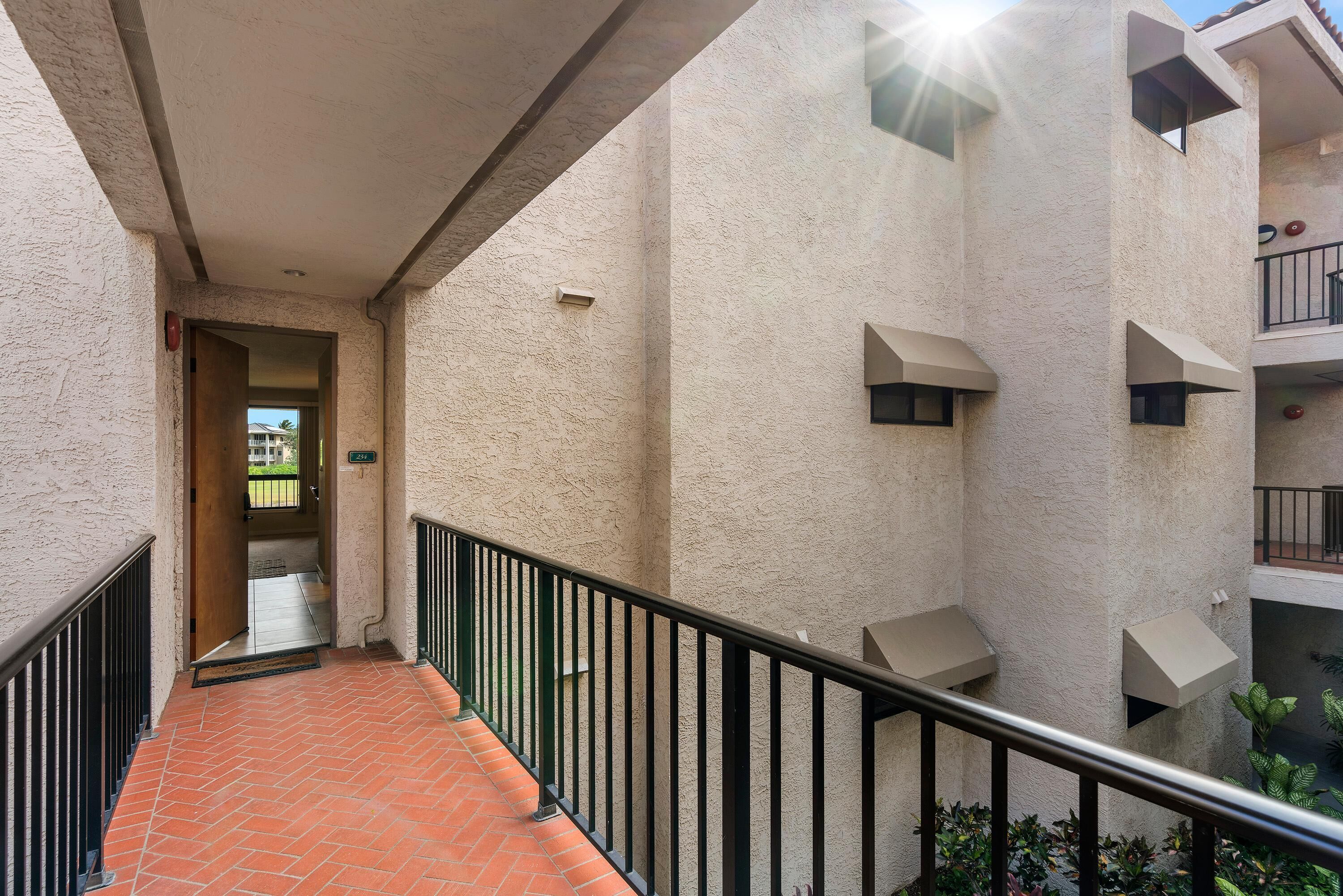 A narrow corridor with a tiled floor and a black railing.