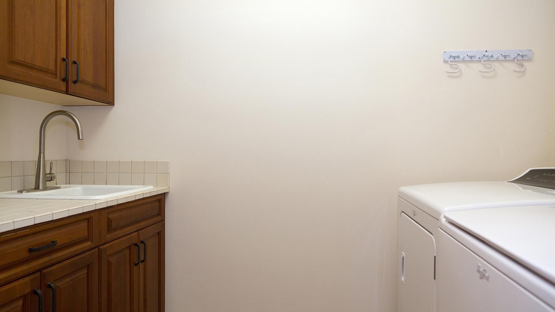 Una cocina con armarios de madera, un lavamanos blanco y una lavadora blanca.
