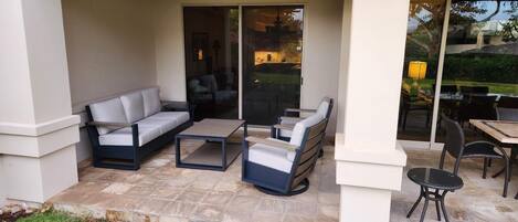 An outdoor patio area with a sofa, a coffee table, and a dining table with chairs.