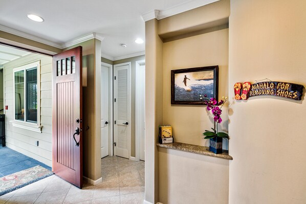 A hallway with a wooden door, a framed picture, and a sign on the wall. - Waikoloa Beach Villas G2 (Waikoloa)