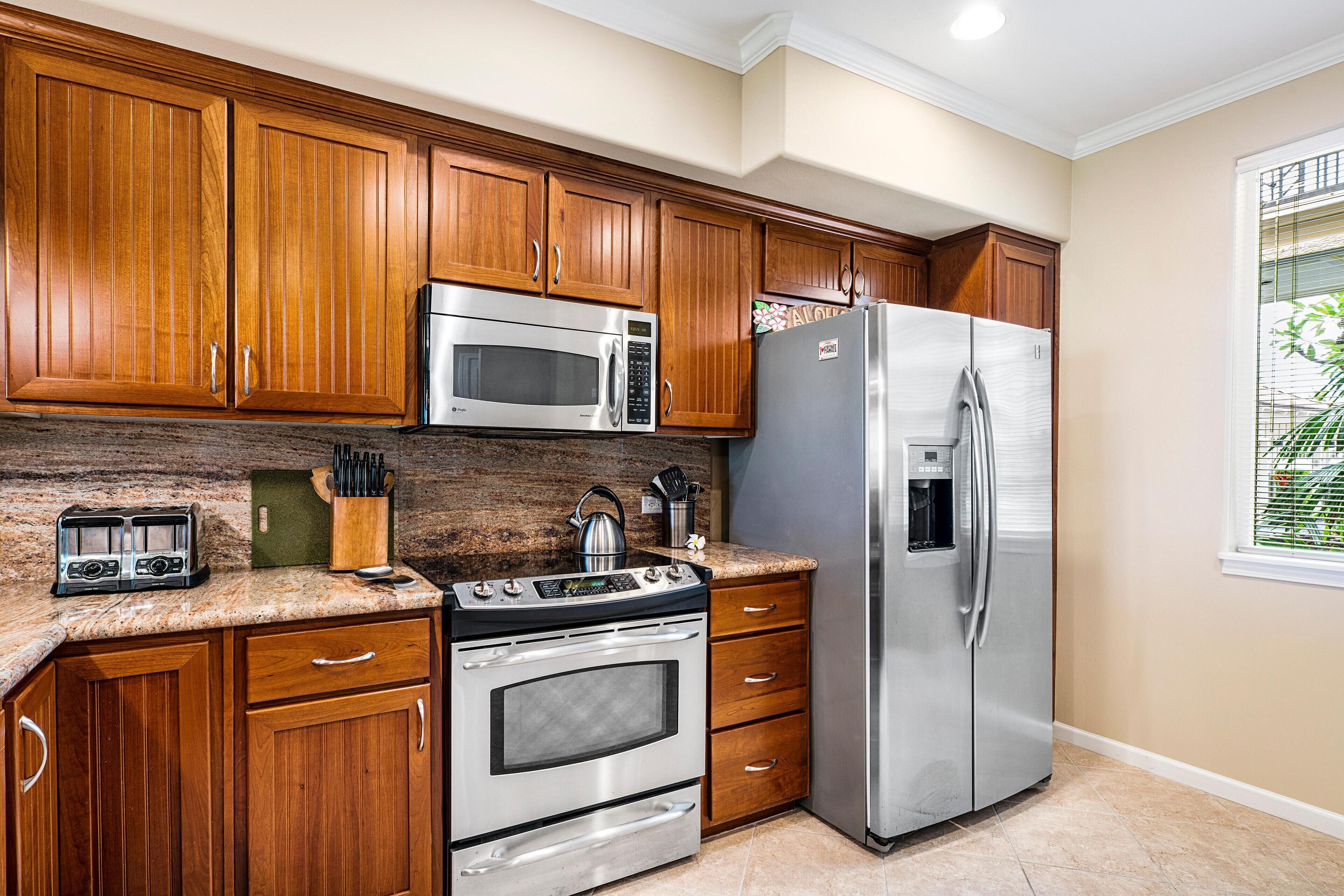 A kitchen with wooden cabinets, stainless steel appliances, and a granite countertop.