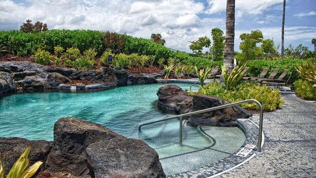 A pool area with clear water, surrounded by rocks and greenery, and a pathway leading to lounge chairs. - Waikoloa Beach Villas J32 (Waikoloa)
