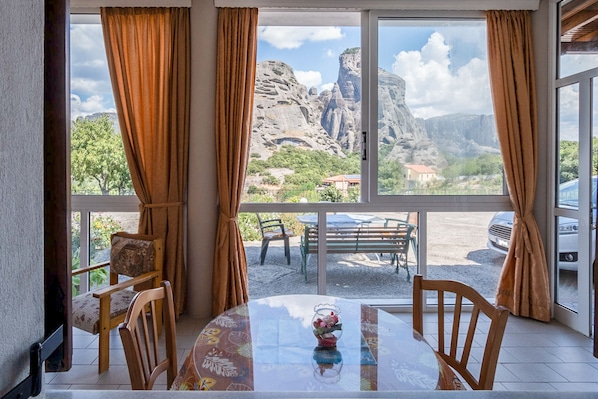 Enjoy breathtaking views of the surrounding mountains from this room's expansive window, featuring a round table and comfortable seating for two.