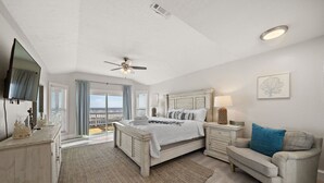 Une chambre à coucher comprenant un lit, une table de chevet, une commode, une chaise et un ventilateur de plafond.