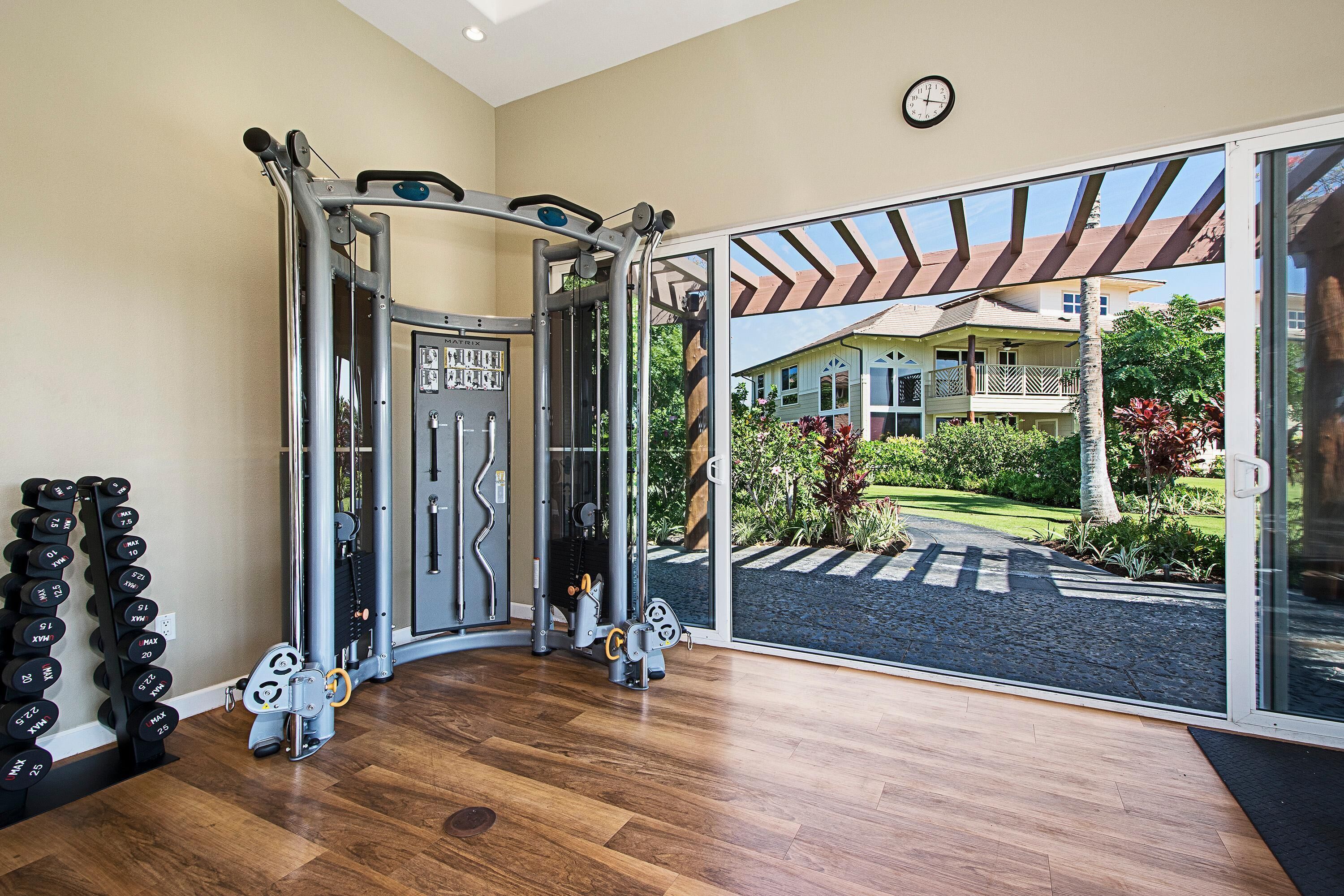 A gym with weight machines, a squat rack, and a set of dumbbells.