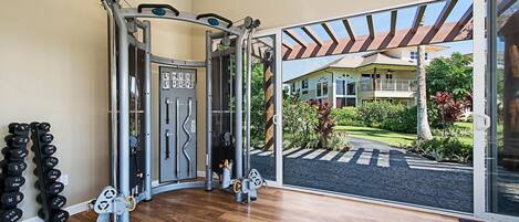 A gym with weight machines, a squat rack, and a set of dumbbells.
