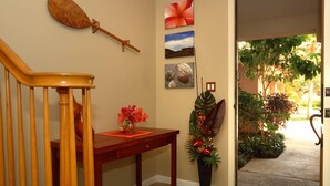 Eine Holztreppe führt zu einer Zwischenebene mit einer Vase roter Blumen, einem Holztisch und einer Wand mit drei gerahmten Bildern.