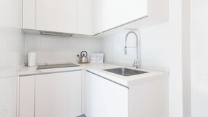 A modern kitchen with white cabinetry, a stainless steel sink, and a kettle on the countertop. - Il Borgo apartments - C3 (Finale Ligure)