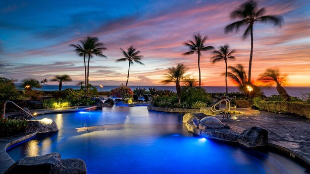 A pool area with palm trees and a sunset view. - Halii Kai at Waikoloa 2B (Waikoloa)