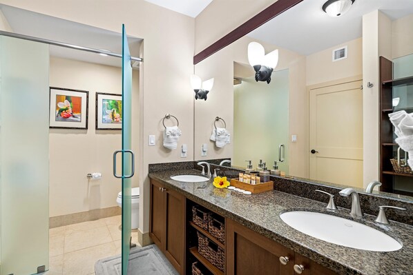 Une salle de bain moderne avec deux vasques, un grand miroir et une porte de douche en verre.