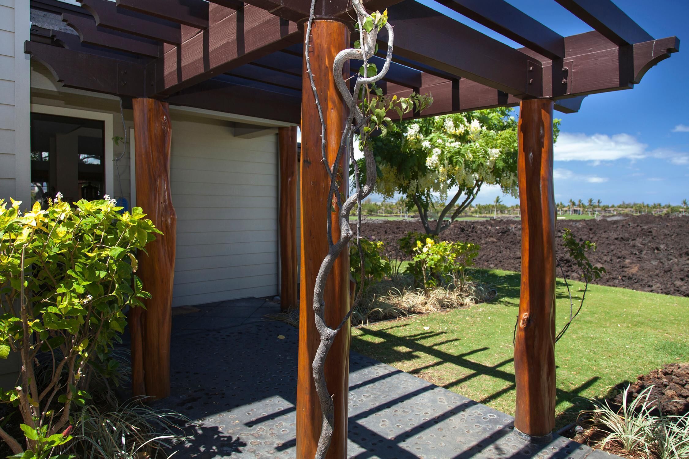 Une pergola en bois, avec une vigne qui grimpe le long de l’un des poteaux.