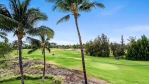 A golf course with palm trees, a well-maintained green, and a golf cart. - Waikoloa Beach Villas P32 (Waikoloa)